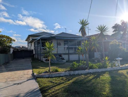 a house with palm trees in the yard at Lake Views at Primbee in Primbee