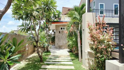 a walkway in front of a house with palm trees at Villa Rajapruek Private Villa 3 houses combine near Airport in Chiang Mai