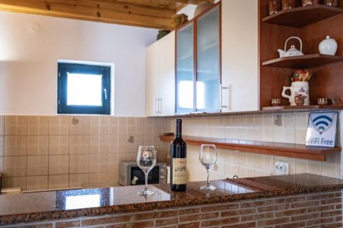 a bottle of wine sitting on a counter with two wine glasses at Guest house Holiday in Žabljak