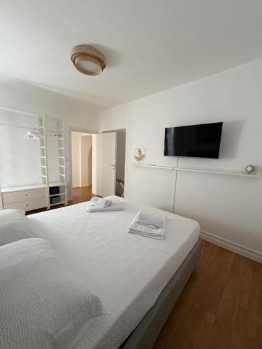 a white bedroom with a bed and a flat screen tv at Fanzago Home in Pisogne