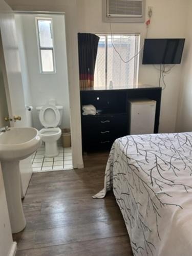 a bathroom with a bed and a sink and a toilet at Encore Inn Inglewood in Inglewood