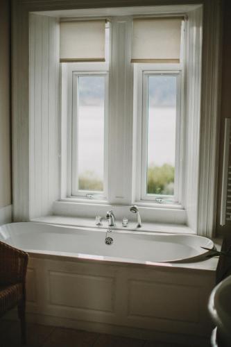 a bath tub in a room with two windows at The Lodge On The Loch Onich in Onich