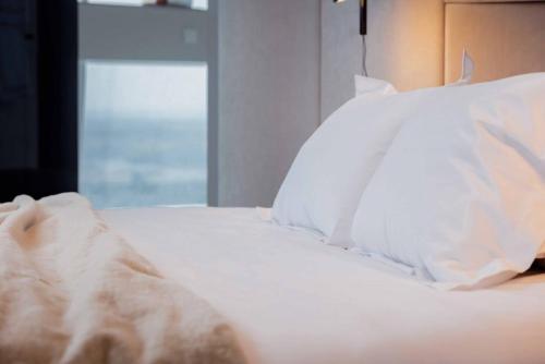 a white bed with white sheets and pillows at Vilnius TV Tower Apartments DEBESYS in Vilnius