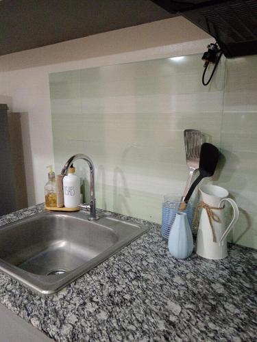 a kitchen counter with a sink and utensils at Sweet Escape 305 at Amaia Steps in Bacolod