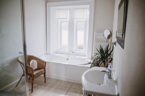 a bathroom with a tub and a sink and a window at The Lodge On The Loch Onich in Onich