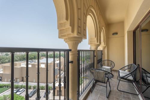 a balcony with chairs and a view of a building at Free housekeeping visits during your stay - StayShort - Stylish 1-Bedroom Retreat with Pool in Vibrant Jumeirah Golf Estates in Dubai