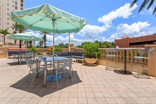 Un patio con mesas y sillas y una sombrilla. en Hampton Inn & Suites St. Petersburg/Downtown, en San Petersburgo