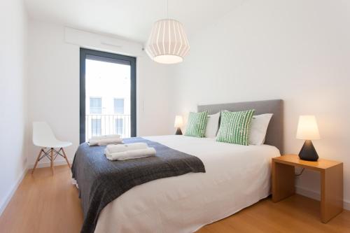 a white bedroom with a large bed and a window at FLH Martim Moniz Modern Flat in Lisbon