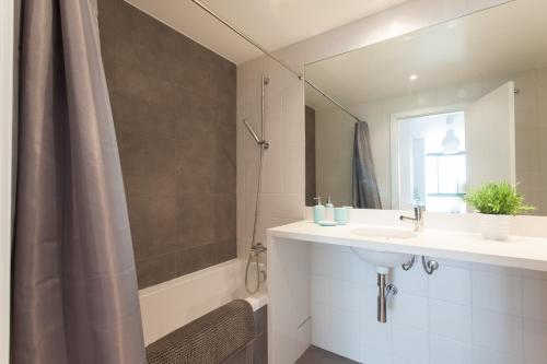 a bathroom with a sink and a shower with a mirror at FLH Martim Moniz Modern Flat in Lisbon