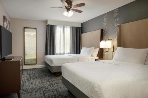a hotel room with two beds and a flat screen tv at Homewood Suites by Hilton Burlington in Burlington