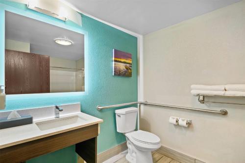 a bathroom with a toilet and a sink and a mirror at La Quinta by Wyndham Batavia in Batavia
