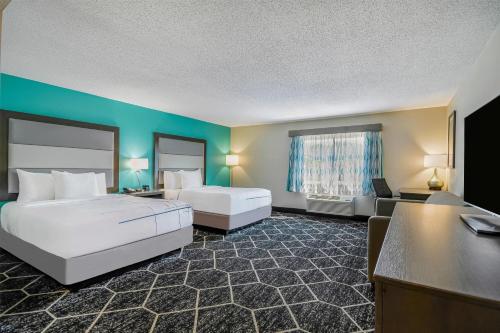 a hotel room with two beds and a desk at La Quinta by Wyndham Batavia in Batavia