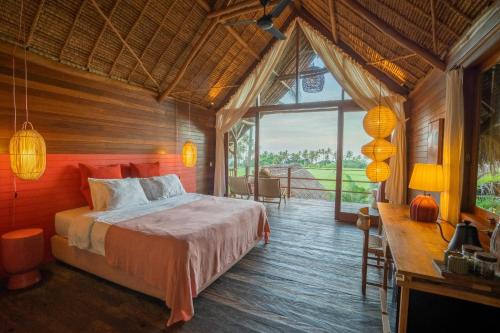 a bedroom with a bed and a large window at Supersenang Boutique Resort Balian in Balian