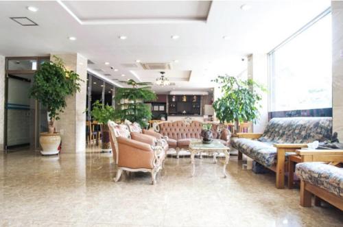 a lobby with couches and tables and plants at Hotel G in Jeju