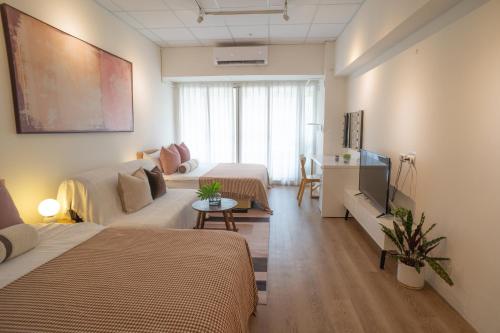 a room with two beds and a couch and a television at 樂居 台北 in T'ung-ko