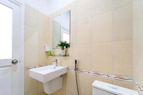 a white bathroom with a sink and a mirror at The Sim Hotel Vung Tau in Vung Tau