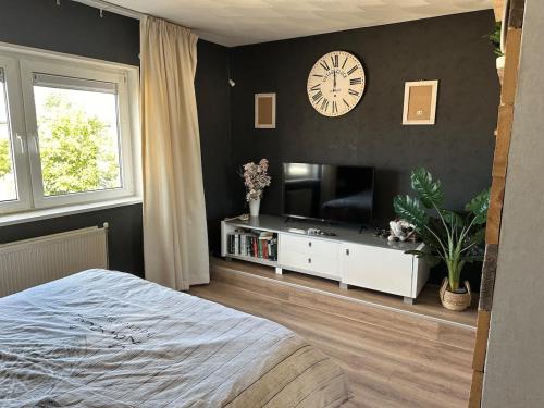a bedroom with a clock on the wall and a tv at Paleisje aan zee in IJmuiden
