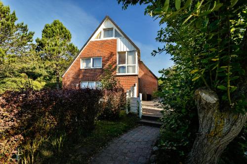 a red brick house with a pathway in front of it at Hotel am Südwäldchen in Westerland (Sylt)
