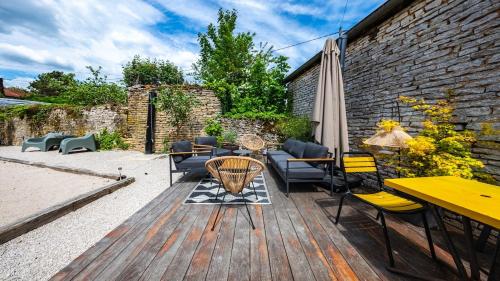 a wooden deck with chairs and tables and an umbrella at L'Ombelle in Selongey