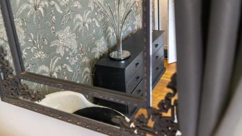a mirror reflecting a bathroom with a sink and a lamp at L'Ombelle in Selongey