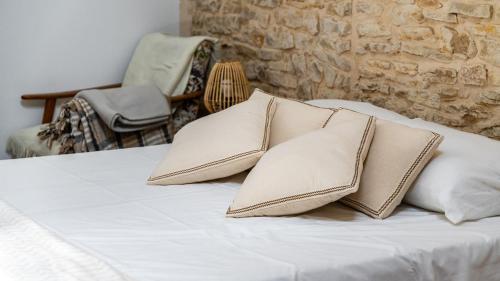 a bed with four pillows on it with a chair at L'Ombelle in Selongey