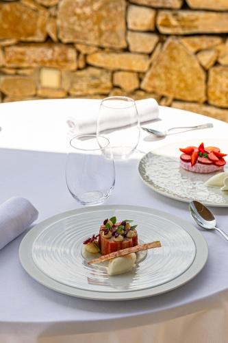 a white plate with a piece of food on a table at Mas des Herbes Blanches Hôtel & Spa – Relais & Châteaux in Joucas