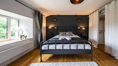a bedroom with a black bed and a window at L'Ombelle in Selongey