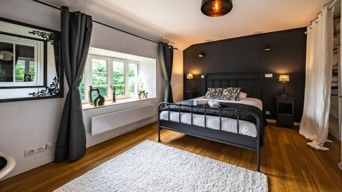 a bedroom with a black bed and a window at L'Ombelle in Selongey