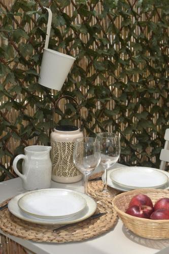 a table with plates and glasses and a basket of apples at Escapade Ibiza Balneo & Terrasse in Sorgues