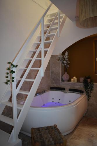 a bathroom with a bath tub under a staircase at Escapade Ibiza Balneo & Terrasse in Sorgues
