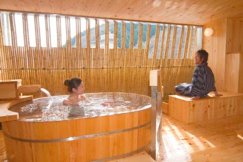 a man and a woman sitting in a hot tub at Asanoya in Shinonsen