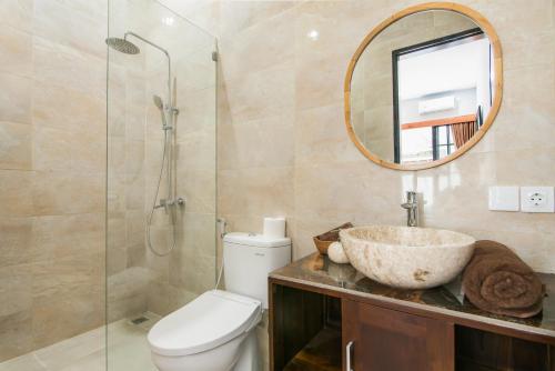 a bathroom with a sink and a toilet and a mirror at Villa Griya Impian in Sanur