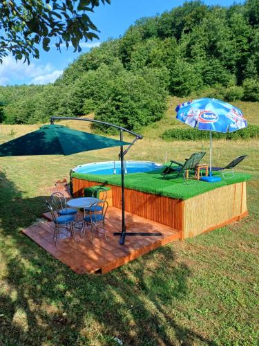 a hot tub with a table and an umbrella at Apartman Denis Una in Lužine