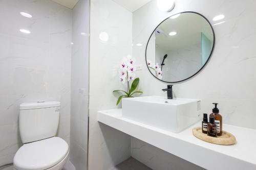 a white bathroom with a sink and a mirror at 樂居 台北 in T'ung-ko