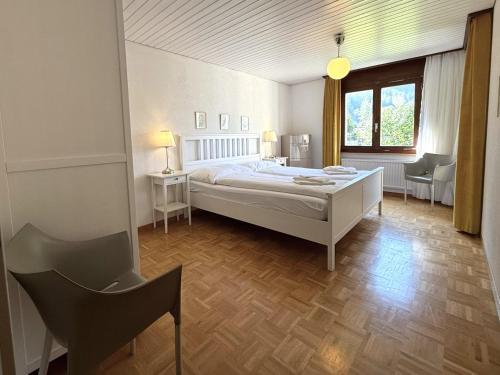 une chambre avec un lit blanc et une grande fenêtre dans l'établissement Royal 41, à Loèche-les-Bains