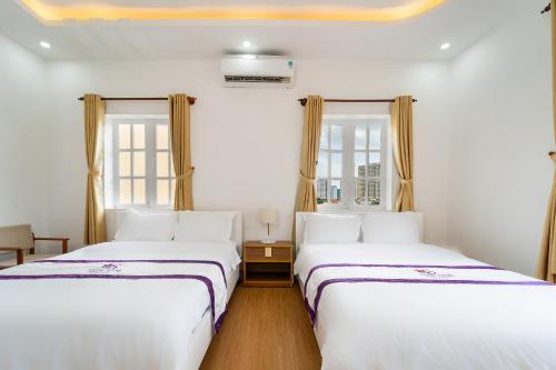 two beds in a room with two windows at The Sim Hotel Vung Tau in Vung Tau