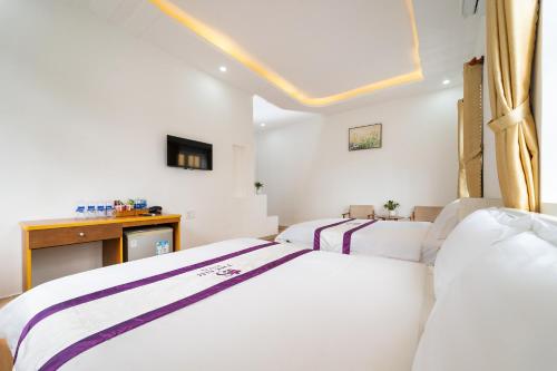 two beds in a room with white walls at The Sim Hotel Vung Tau in Vung Tau