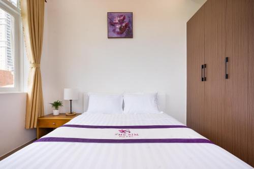 a bedroom with a large white bed and a window at The Sim Hotel Vung Tau in Vung Tau