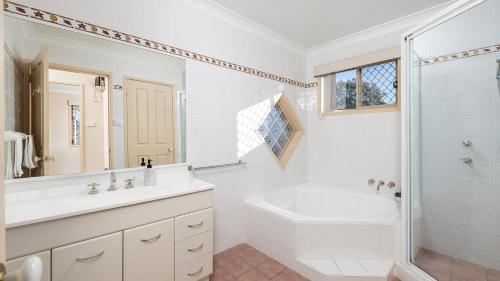 Un baño blanco con lavabo y ducha. en Shoal Bay Townhouse with Spa, en Shoal Bay