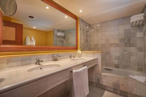 a bathroom with a sink and a tub and a mirror at Hipotels Eurotel Punta Rotja Spa-Golf in Costa des Pins