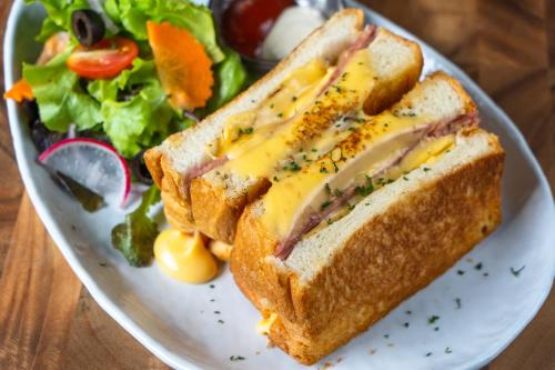 ein Sandwich mit Käse und einem Salat auf einem Teller in der Unterkunft Siri Village Chiang Mai in Chiang Mai