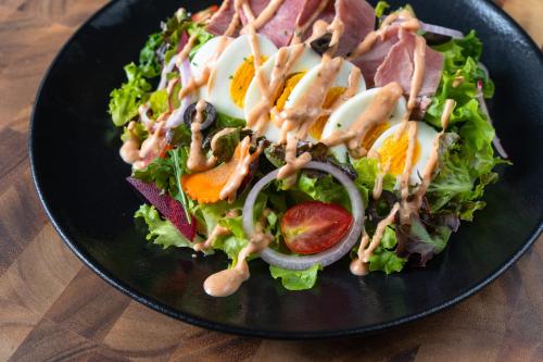 ein schwarzer Teller mit einem Salat mit Dressing darauf in der Unterkunft Siri Village Chiang Mai in Chiang Mai