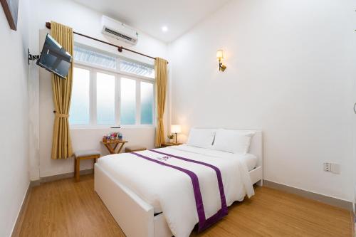 a white bedroom with a large bed and a window at The Sim Hotel Vung Tau in Vung Tau