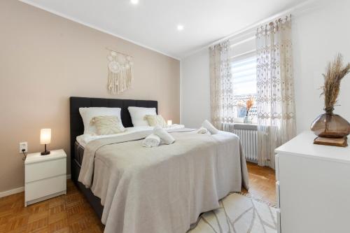 a white bedroom with a large bed and a window at Stay COZY - TOP LAGE - Kingsize Betten - Parkplatz - Balkon - Netflix in Aschaffenburg