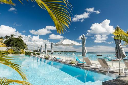 a swimming pool with lounge chairs and umbrellas at OBiches Penthouse C1 Beachfront Complex in Trou aux Biches