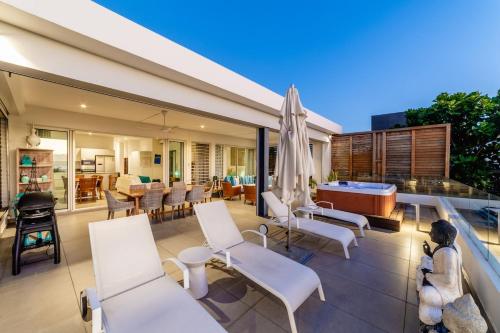a patio with white chairs and a pool table at OBiches Penthouse C1 Beachfront Complex in Trou aux Biches