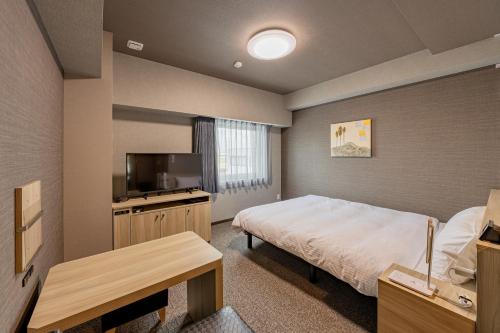 a small bedroom with a bed and a television at Hotel Route Inn Kanegasaki 