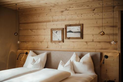 a bed with white pillows in a room with wooden walls at Hotel Spielmann in Ehrwald