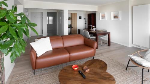 a living room with a brown leather couch and a table at Valdemosa one in De Haan