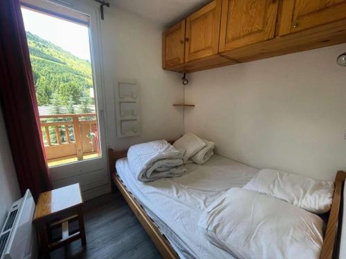 un lit dans une chambre avec une grande fenêtre dans l'établissement Résidence Alpina 3 - Agréable appartement T3 secteur calme pied des pistes MAE-5481, à Vénosc